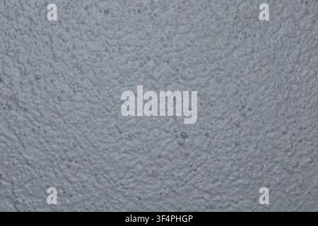 Neutral gray textured surface with a fine rough pattern, suitable as a background or abstract texture. Stock Photo