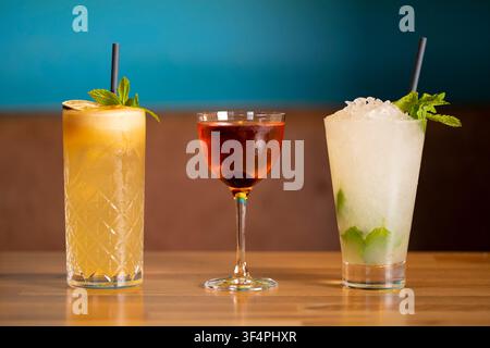 Three Colorful Cocktails Displayed on a Wooden Table in a Vibrant Bar Setting Stock Photo