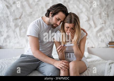 Worried Caucasian Woman Reviewing Pregnancy Test With Supportive Partner At Home, Healthcare Concept Stock Photo