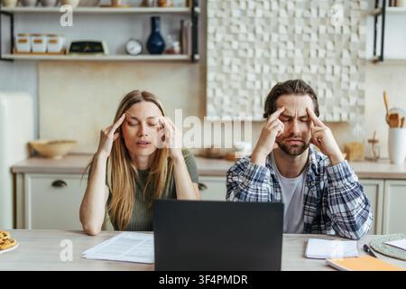 Stressed Caucasian Man And Woman Working On Laptop At Home, Feeling Overwhelmed Stock Photo