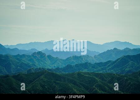 A wide, horizontal landscape features numerous mountain ridges fading from dark green in the foreground to light blue-grey in the distant background. Stock Photo