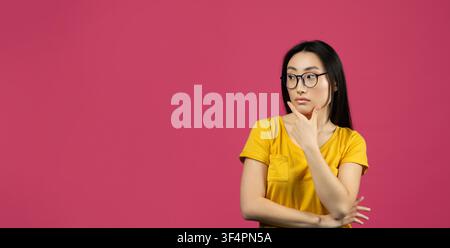 Thoughtful Young Asian Woman In Glasses Pondering Ideas, Pink Background, Business Concept Stock Photo