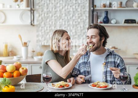 Happy Young Couple Enjoying Pasta Dinner At Home, Smiling Together, Food And Love Concept Stock Photo
