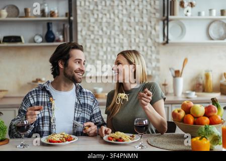 Happy Caucasian Couple Enjoying Dinner Together In Kitchen, Eating Spaghetti, Lifestyle Concept Stock Photo