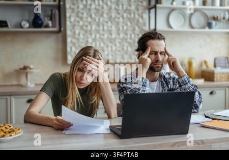 Worried Caucasian Couple Reviewing Financial Documents At Home, Stressful Situation Stock Photo