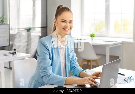 Smiling businesswoman accountant working on laptop in bright modern office interior Stock Photo