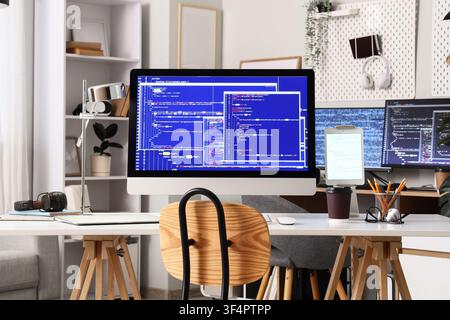 Modern home office workspace with multiple computer screens displaying programming code and development software development Stock Photo