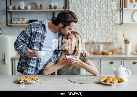 Happy Couple Enjoying Breakfast Together At Home, Sharing Coffee And Smiles Stock Photo