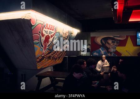 Buenos Aires, Argentina - July 26, 2026: Unidentified women sitting in a restaurant with a graffiti on the back in the Buenos Aires Chinatown in CABA, Stock Photo