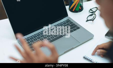 Person Using Laptop At Office Desk With Notepad And Glasses, Unrecognizable, Business Concept Stock Photo