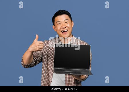 Happy Asian Male Holding Laptop And Giving Thumbs Up, Business Concept Stock Photo