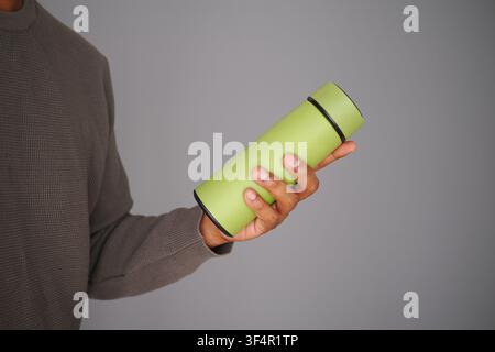 Holding a green thermos in a home setting Stock Photo