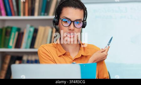 Focused Young Latina Woman Using Headset Teaching Online Class In Home Office, Business Concept Stock Photo