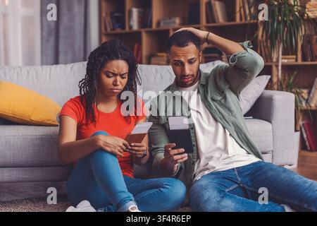 Worried Black Woman And Man Reviewing Documents Together At Home, Financial Concept Stock Photo