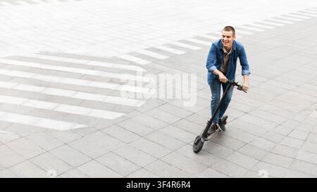 Happy guy having pleasant ride on electric kick scooter Stock Photo