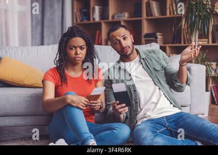 Concerned Black Woman And Man Discussing Financial Matters At Home, Serious Situation Stock Photo