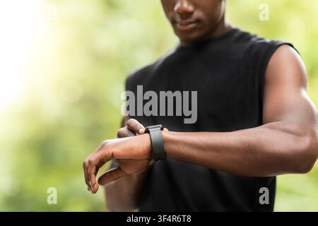 Cropped of black sportsman using his smartwatch Stock Photo