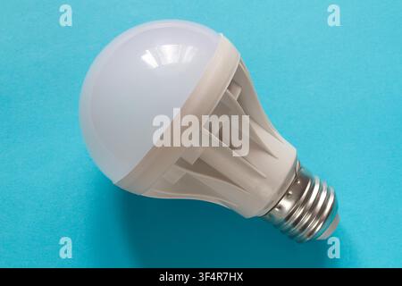 Modern LED lamp for room lighting. The lamp is close-up on a blue textured background. Stock Photo
