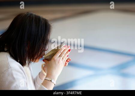 Chanoyu, or the Japanese tea ceremony. A woman seen in profile drinking a bowl of matcha tea. Stock Photo