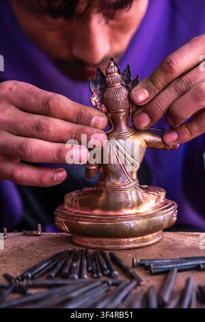 Norbulingka Institute, Sidhpur, Himachal Pradesh, India. A craftsman is working on a metal statue in his workshop. The tools are laid out on the workb Stock Photo