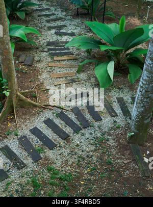 A winding garden path featuring rectangular stepping stones laid over small light-colored pebbles Stock Photo