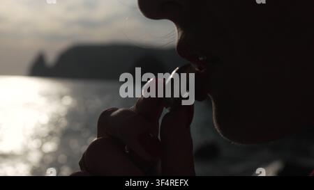 Silhouette ring sunset glittering ocean woman holding shiny jewelry against sparkling sea backdrop. Stock Photo