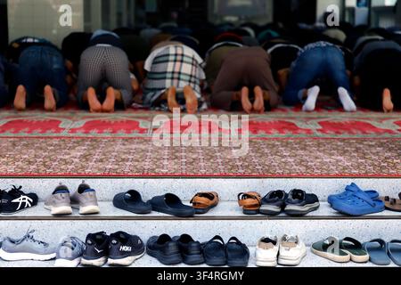 Worshippers praying inside the Grand Mosque of Saigon. Their shoes are left outside. Stock Photo