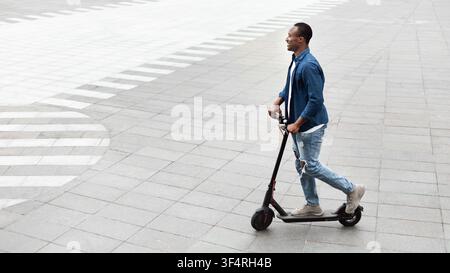 Black man having pleasant ride on electric kick scooter Stock Photo