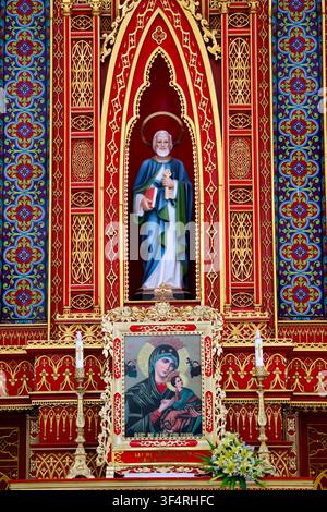 Lang Van Church. Statue of Saint Peter holding keys and a book, in front of an icon of Our Lady of Perpetual Help. Gia Van. Vietnam. Stock Photo