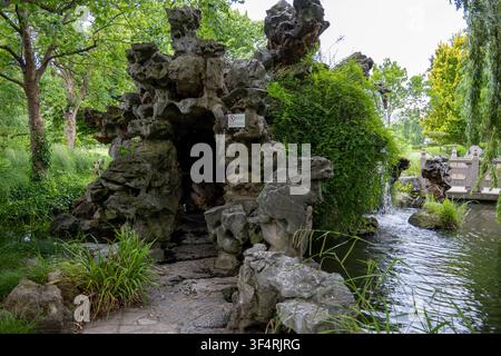 Artificial rock grotto with small waterfall and pond in the garden landscape of Luisenpark in Mannheim, Baden-Wurttemberg, Germany. Stock Photo