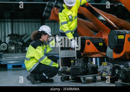 Industrial engineers team checking servo motor for robotic arm maintenance in warehouse. Concept of heavy industrial machinery maintenance service, eq Stock Photo