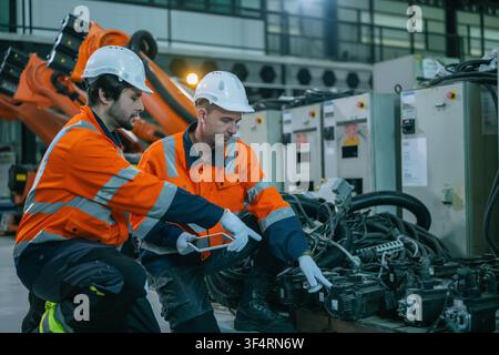 Automation technicians team holding digital tablet checking robotics motor equipment quality control workshop. Concept of heavy machinery repair, tech Stock Photo