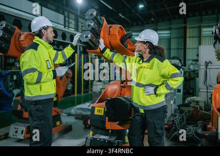 Two industrial engineers male and female inspecting automated machinery on factory floor. Concept of smart factory automation system control, robotics Stock Photo