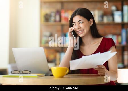 Remote Office. Young Asian Businesswoman Working With Papers And Phone In Cafe Stock Photo