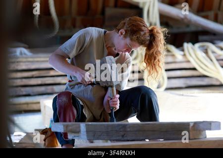 Carpenters' workshop. A woman is working with wood as part of the construction of the medieval castle at Guédelon. Treigny, France. Stock Photo