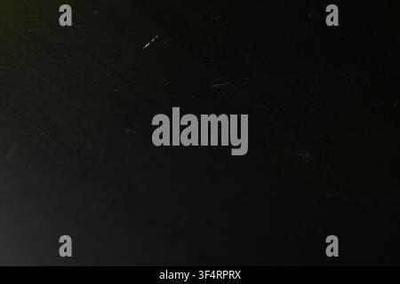 Abstract dark surface with faint diagonal streaks suggests rain at night. Subtle highlights and soft gradients create a minimal moody texture for back Stock Photo