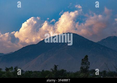 Mountain landscape in Nagri, Himachal Pradesh, India, with clouds illuminated by the setting sun standing out against the blue sky Stock Photo