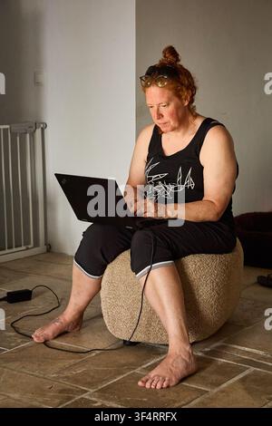 A red-haired woman working on a laptop from home Stock Photo