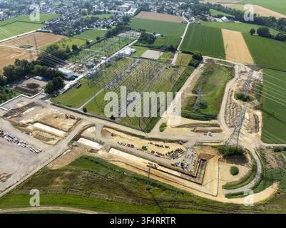 Aerial view of the Neufinsing electrical substation with power lines, construction equipment, and surrounding agricultural fields in Finsing, Bayern, Stock Photo