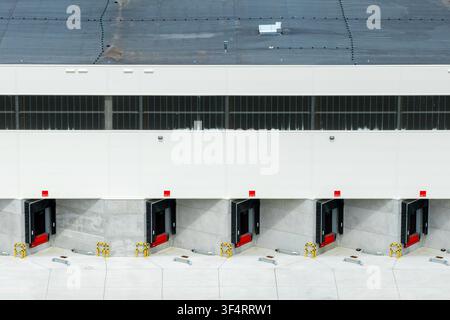 Aerial view of a modern industrial warehouse featuring multiple loading docks with red levelers and concrete walls in Poland. Stock Photo