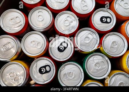 A close-up view of numerous colorful beverage cans—mostly red, green, and yellow—stacked up and ready to be enjoyed. The condensation on their surface Stock Photo