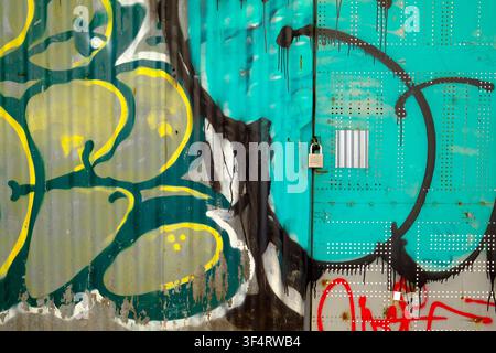 A corrugated metal surface features colorful graffiti with abstract shapes and paint drips. Street art. Ho Chi Minh City. Vietnam. Stock Photo