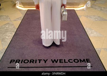 Hoa Lu, Vietnam. A woman in white pants stands on a "Priority Welcome" carpet. Elegance and style abound at this luxury hotel. Stock Photo
