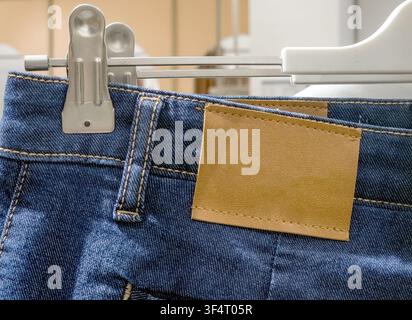 Empty rectangular leather label on waist of casual blue denim jeans hanging in a store Stock Photo