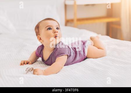 Happy Baby Girl Crawling On Bed With Toy, Indoor Lifestyle, Playing Concept Stock Photo
