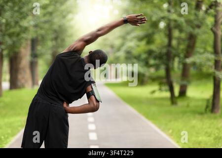 Black sportsman exercising before jogging, back view Stock Photo