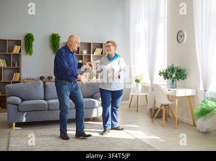 Happy senior couple dancing at home in bright living room, active retirement Stock Photo
