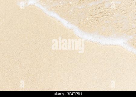 Soft ocean wave foam gently washing over fine golden sand on a tropical beach. Natural coastal texture and copy space. Ayfilon beach Karpaz Stock Photo