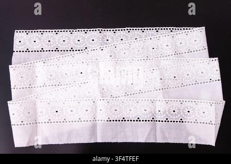 White textile floral lace ribbon trim, delicate cotton embroidery border fabric. Top view embroidered eyelet flower pattern Stock Photo