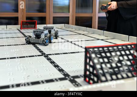 Small robots compete in a technology display at a robotics event in a classroom setting Stock Photo